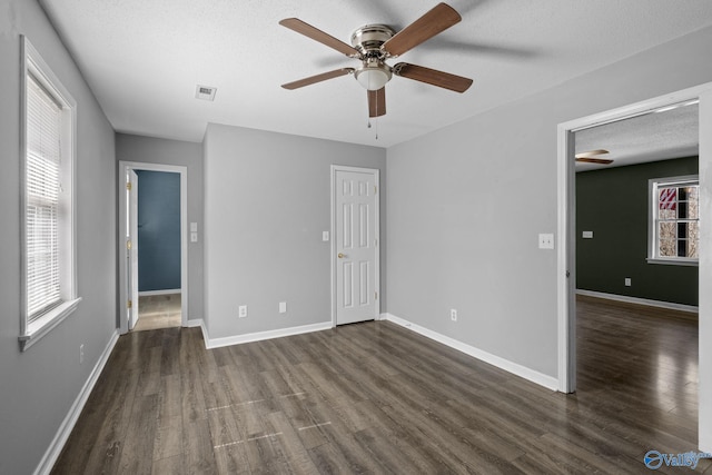 unfurnished bedroom featuring visible vents, baseboards, dark wood finished floors, and a textured ceiling