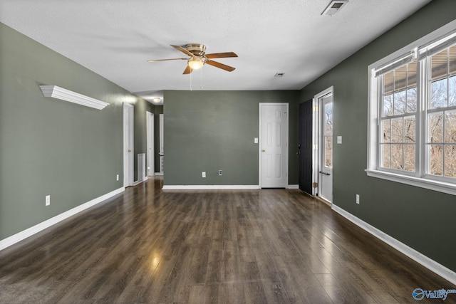 unfurnished room featuring a textured ceiling, dark wood-type flooring, visible vents, and baseboards