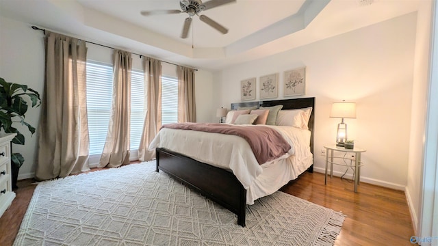 bedroom featuring ceiling fan, a raised ceiling, and wood-type flooring