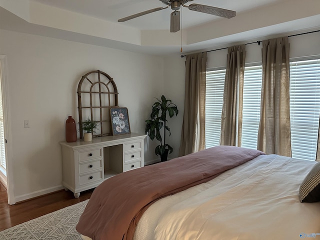 bedroom featuring a tray ceiling, ceiling fan, and dark hardwood / wood-style floors