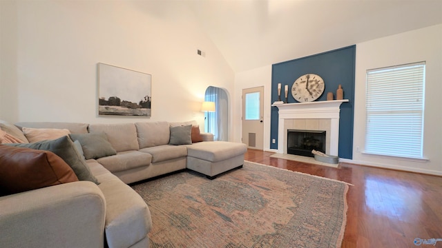 living room with a wealth of natural light, wood-type flooring, a fireplace, and high vaulted ceiling