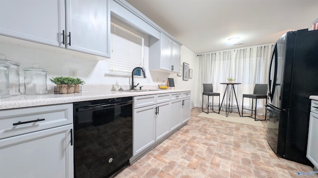 kitchen with white cabinets, sink, light stone counters, and black appliances