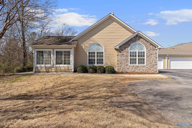 single story home featuring a garage, stone siding, and aphalt driveway