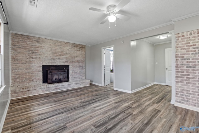 unfurnished living room featuring ceiling fan, dark wood-type flooring, a brick fireplace, a textured ceiling, and ornamental molding