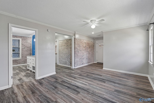 unfurnished room with dark hardwood / wood-style flooring, ornamental molding, a textured ceiling, and brick wall