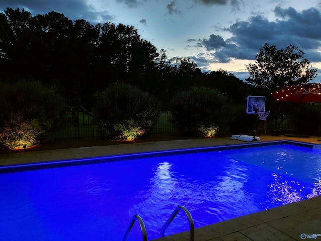 pool at dusk featuring a fenced in pool and fence