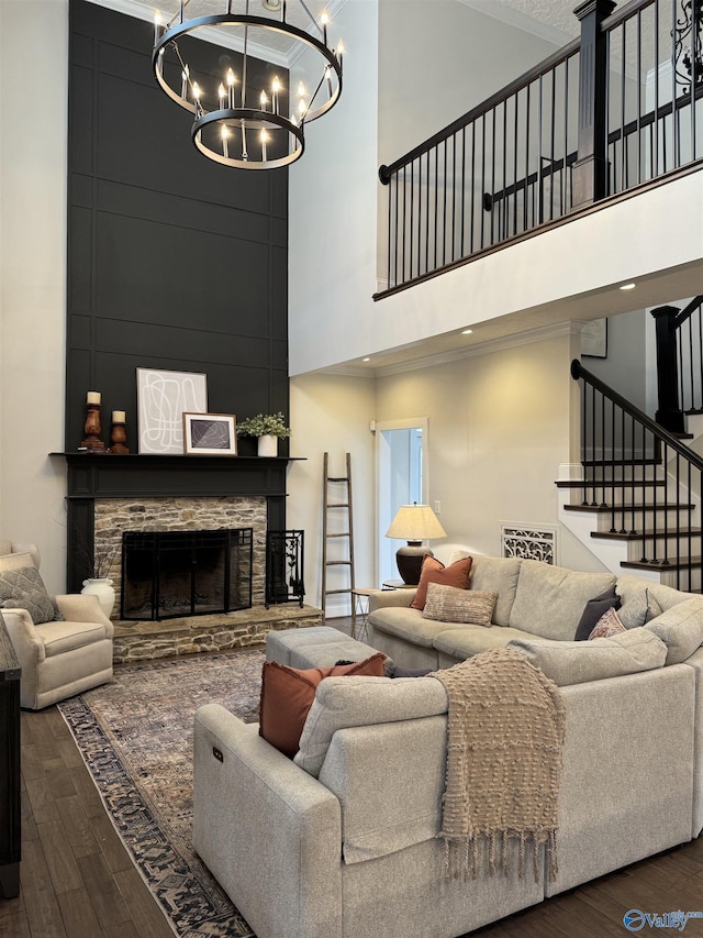 living room with a stone fireplace, stairway, a high ceiling, and wood finished floors