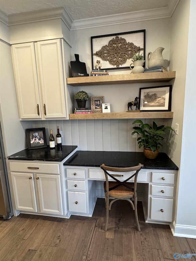 office with dark wood-style floors, ornamental molding, and built in desk