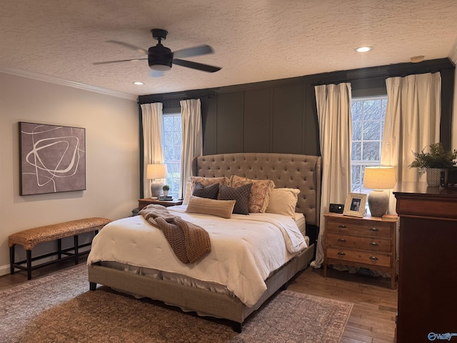 bedroom with ceiling fan, crown molding, wood finished floors, and a textured ceiling