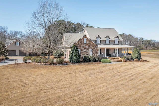 view of front of property with a porch, driveway, a front lawn, and stone siding