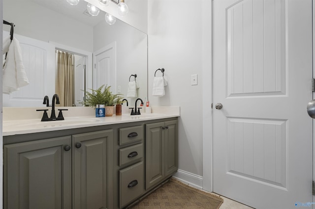 full bathroom featuring a sink, baseboards, double vanity, and tile patterned floors