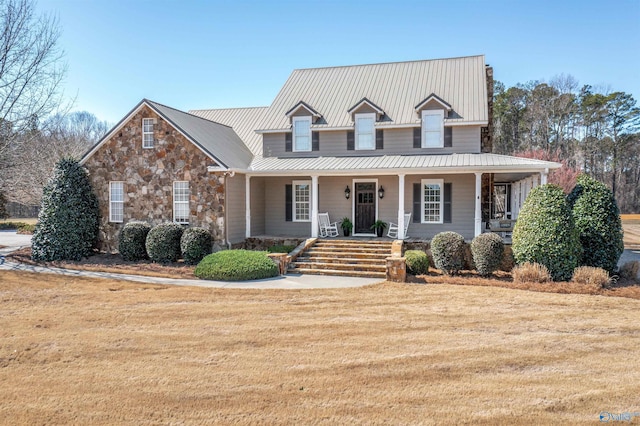 view of front of home featuring a front lawn, a porch, stone siding, and metal roof