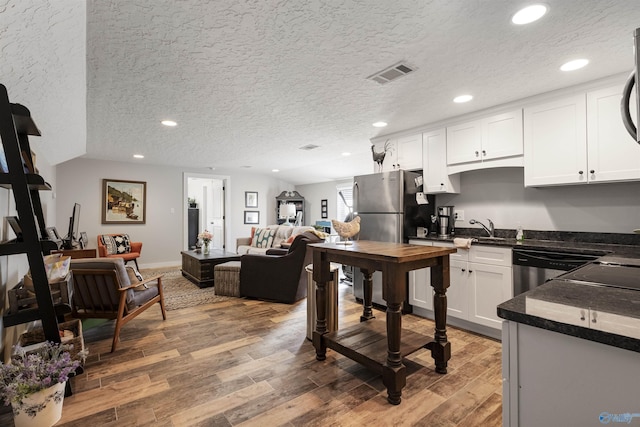 kitchen with visible vents, light wood-style flooring, dark countertops, recessed lighting, and white cabinets