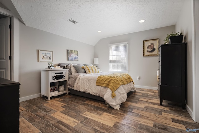 bedroom with lofted ceiling, dark wood-style flooring, and a textured ceiling