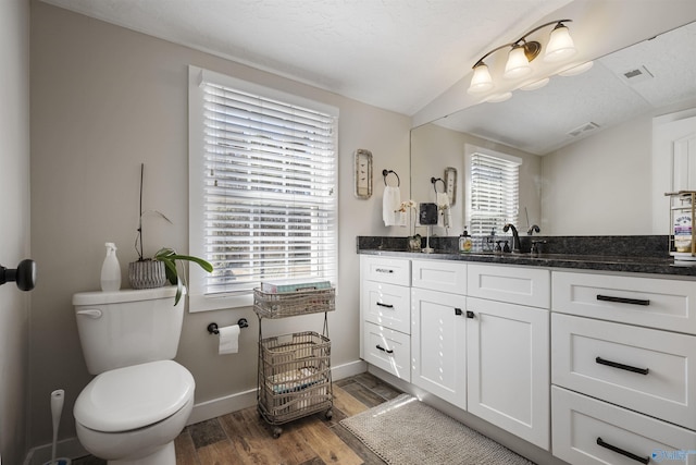 bathroom featuring visible vents, baseboards, toilet, wood finished floors, and vanity