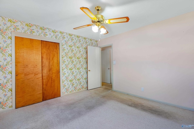 carpeted empty room with baseboards, a ceiling fan, and wallpapered walls