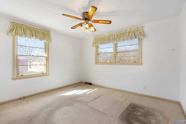 carpeted spare room with a ceiling fan, plenty of natural light, and baseboards