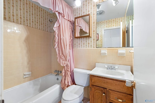 bathroom with toilet, a wainscoted wall, tile walls, shower / bath combo with shower curtain, and wallpapered walls