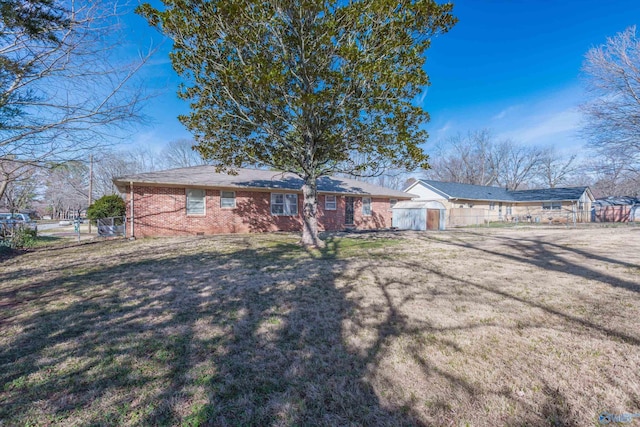 ranch-style home with a shed, fence, a front lawn, and brick siding