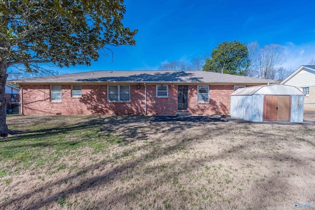 ranch-style house featuring brick siding, a storage unit, a front yard, crawl space, and an outdoor structure