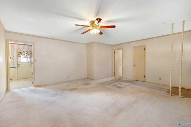 carpeted spare room featuring a ceiling fan and crown molding