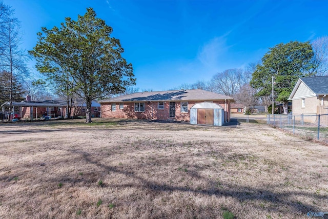 view of front facade featuring an outbuilding, brick siding, fence, a shed, and a front lawn