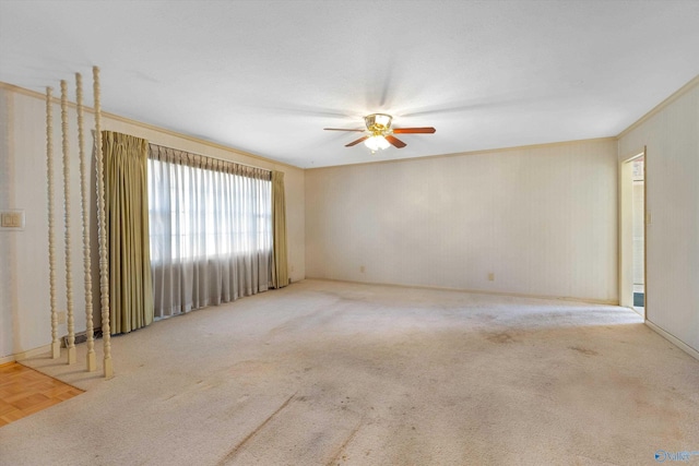 empty room featuring a ceiling fan, crown molding, and carpet flooring