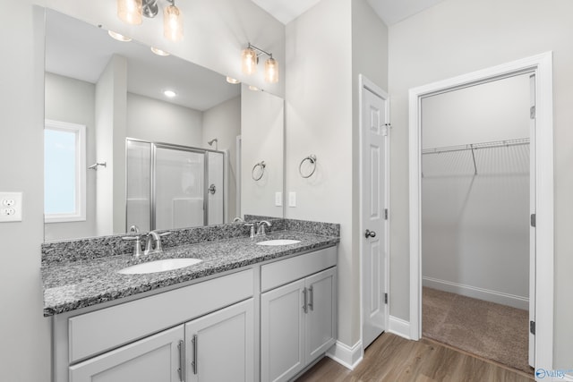 bathroom featuring hardwood / wood-style flooring, vanity, and a shower with door