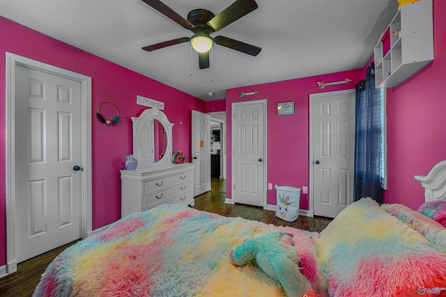 bedroom featuring ceiling fan, dark hardwood / wood-style floors, and two closets