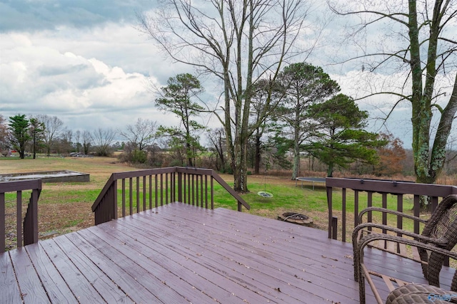 wooden terrace with a trampoline and a yard