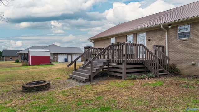 back of house with a fire pit, a yard, and a wooden deck