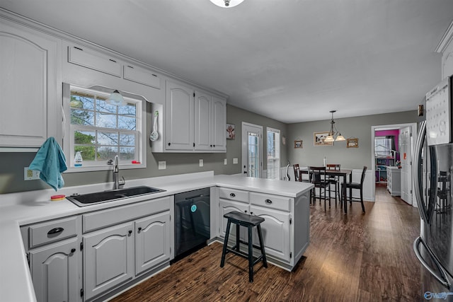 kitchen with sink, black dishwasher, kitchen peninsula, stainless steel fridge, and decorative light fixtures