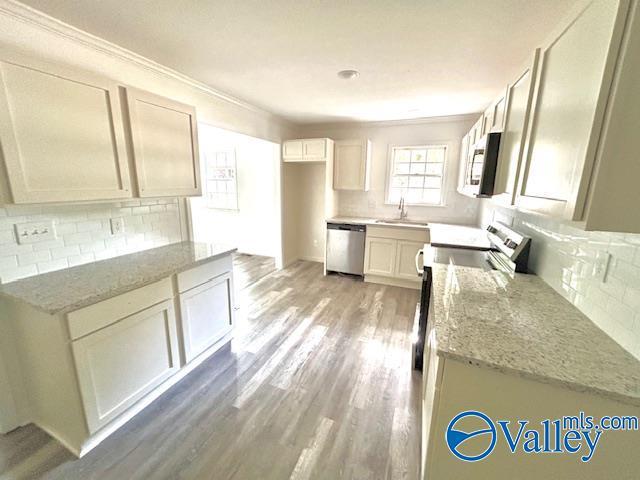 2618 NW Mountain Park Cir, Huntsville, AL 35810 - kitchen featuring appliances with stainless steel finishes, backsplash, light stone counters, and crown molding
