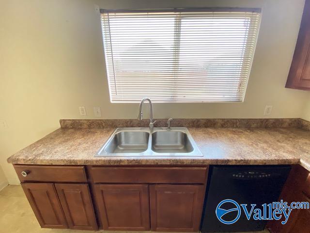 kitchen with dishwasher, light countertops, a sink, and brown cabinetry