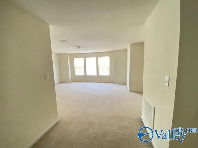 unfurnished room with light carpet, visible vents, and baseboards