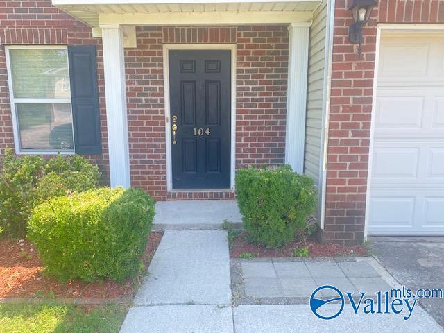 doorway to property featuring an attached garage and brick siding