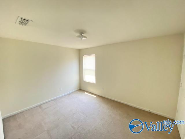 unfurnished room featuring baseboards, visible vents, and carpet flooring