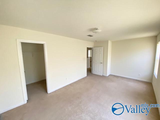 unfurnished room with visible vents, baseboards, and light colored carpet