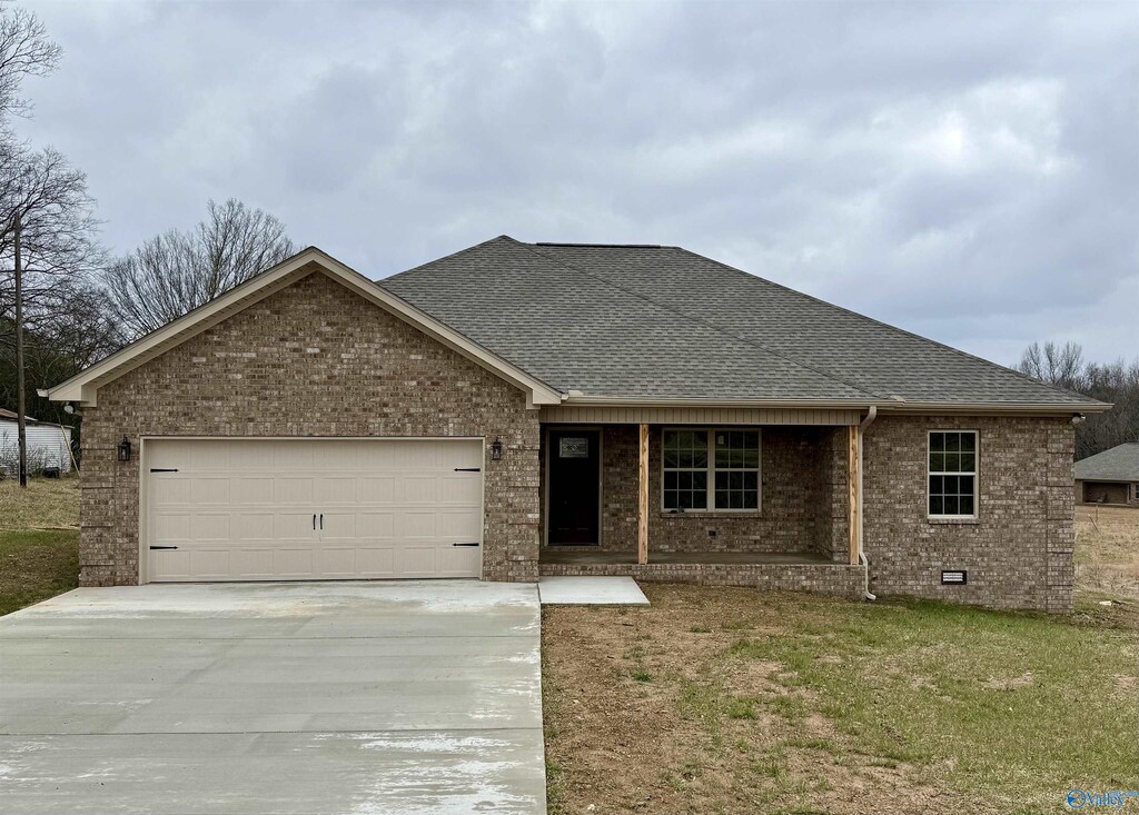 ranch-style house with driveway, an attached garage, brick siding, and roof with shingles