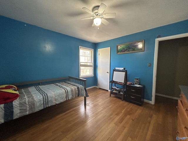 bedroom with ceiling fan, wood finished floors, and baseboards