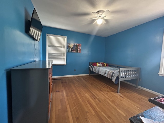 bedroom featuring ceiling fan, baseboards, and wood finished floors