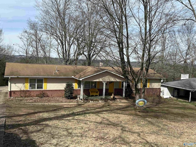 ranch-style house with a front yard, dirt driveway, a chimney, and brick siding