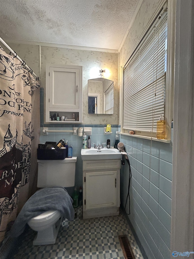 full bath with toilet, tile walls, ornamental molding, and a textured ceiling