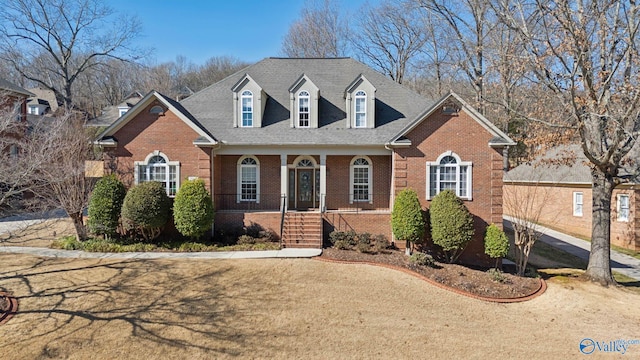 view of front of property featuring covered porch, brick siding, and a front lawn