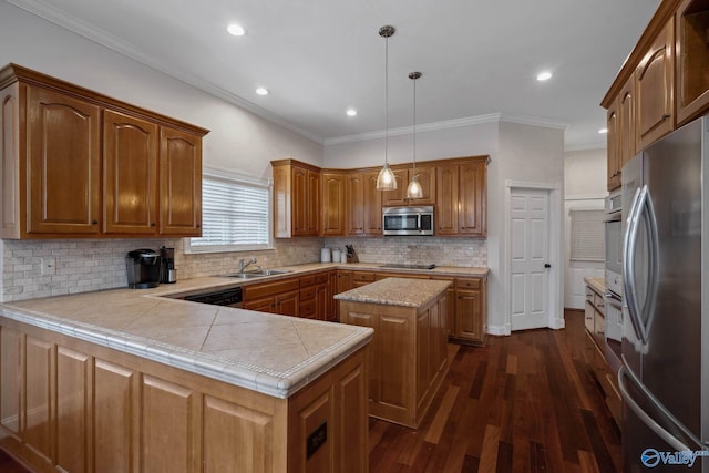 kitchen with a center island, decorative light fixtures, light countertops, appliances with stainless steel finishes, and a sink