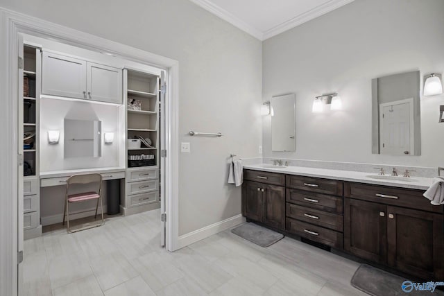 bathroom with ornamental molding, a sink, baseboards, and double vanity