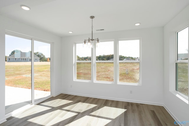 unfurnished dining area featuring dark wood-type flooring, plenty of natural light, and a notable chandelier