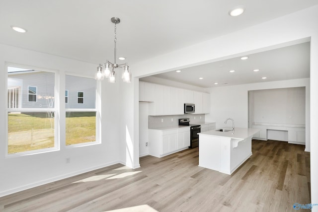 kitchen with sink, a center island with sink, pendant lighting, stainless steel appliances, and white cabinets