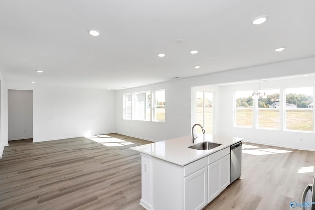 kitchen with sink, white cabinetry, stainless steel dishwasher, an island with sink, and light hardwood / wood-style floors