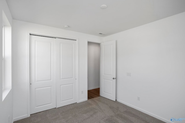 unfurnished bedroom with light colored carpet and a closet